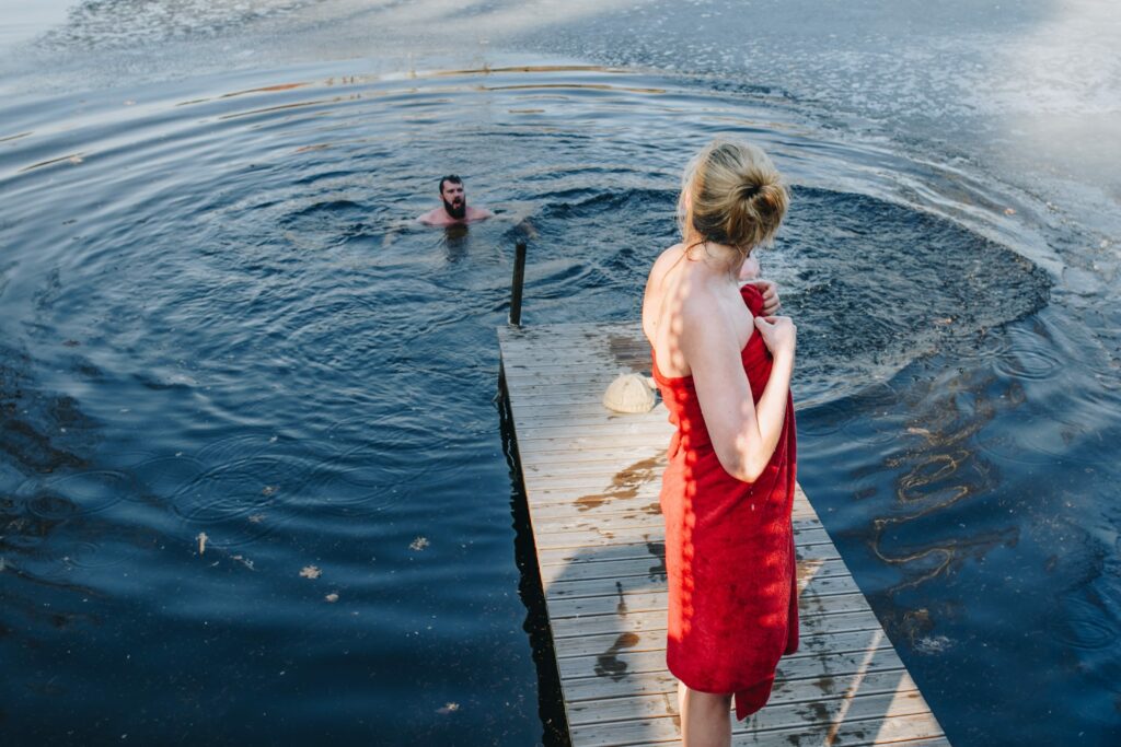 Femme enveloppée dans une serviette regardant un homme qui se baigne dans un lac