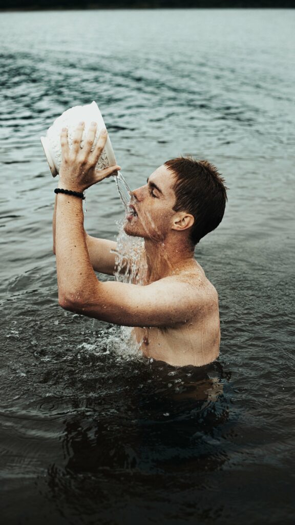 Homme dans un lac se versant de l'eau sur le visage