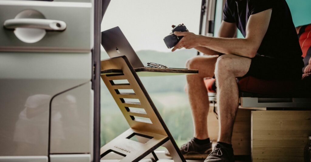 Homme travaillant avec un ordinateur et un appareil photo dans un van