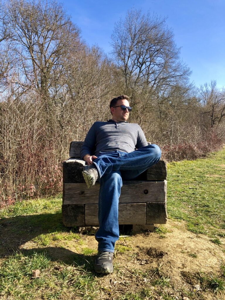 Loïc assis sur un fauteuil en bois près de l'étang de Montréal-du-Gers