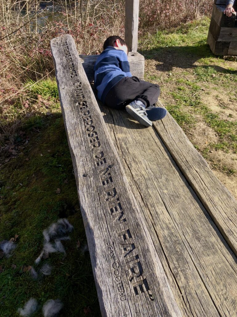 Alexandre assis sur un banc en bois près de l'étang de Montréal-du-Gers